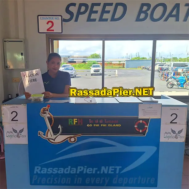 A staff member holding a Check In Here sign at Counter No. 2 for Koh Phi Phi speedboat departures at Rassada Pier